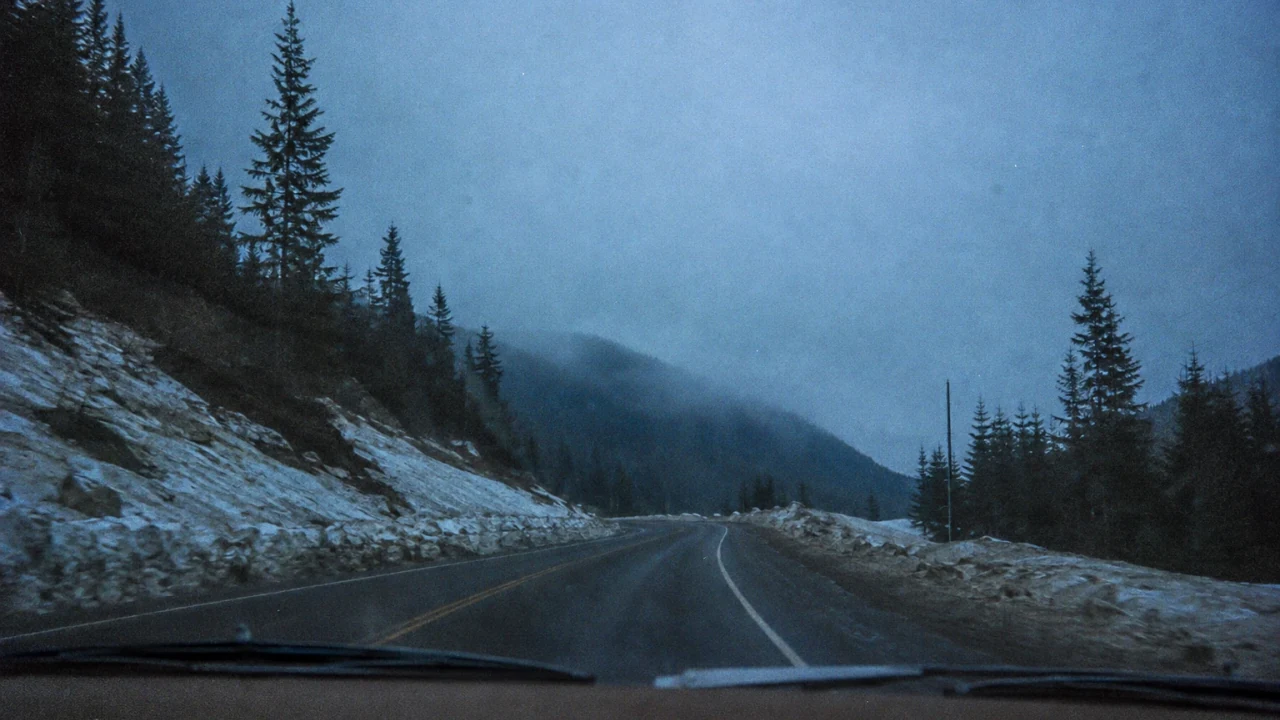 A snowy road into the Cascade foothills, photographed through a car windshield.