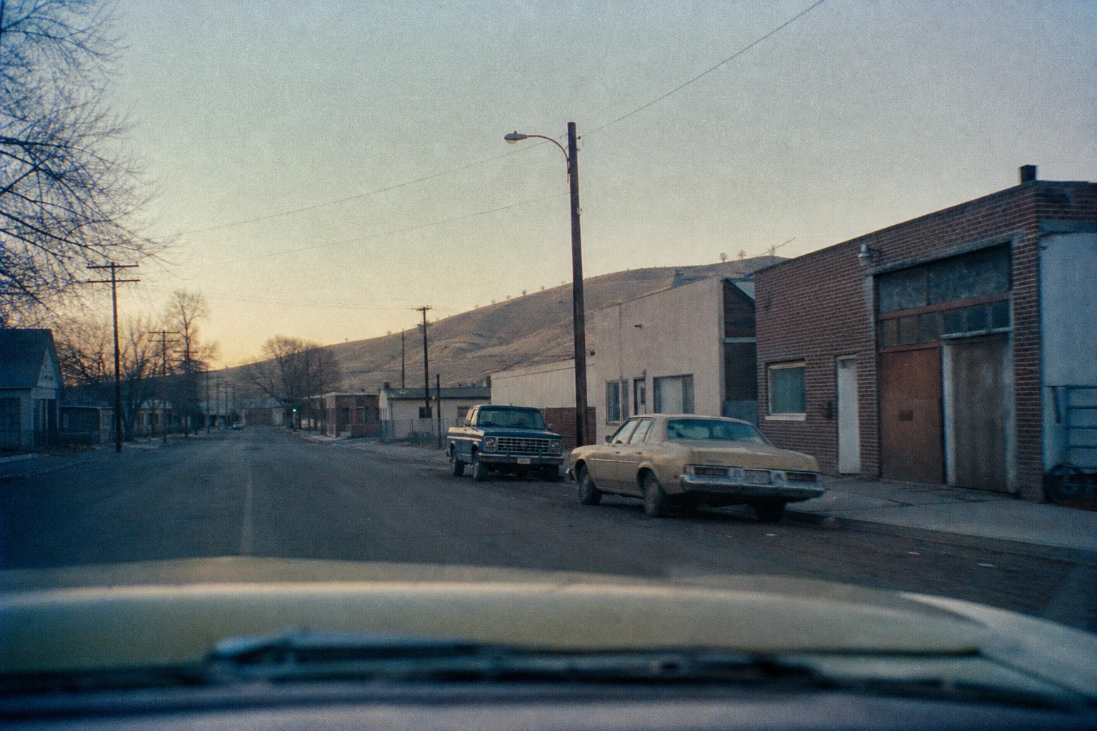 A quiet Yakima street with parked period cars in early morning light.