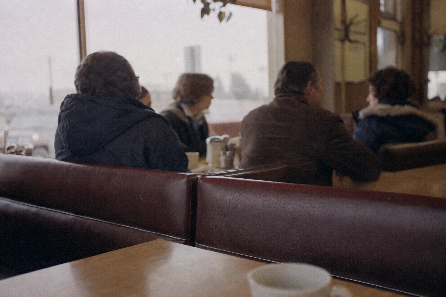 People in winter parkas sitting in a modest 1970s roadside diner.
